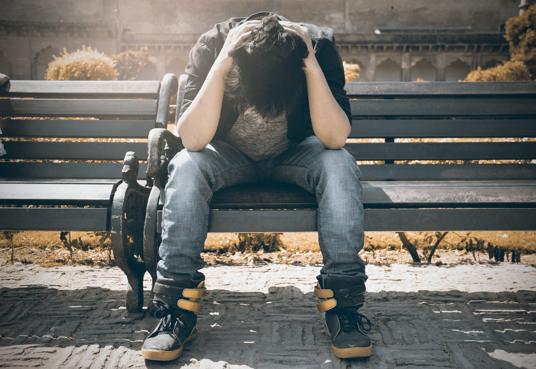 man in black shirt and gray denim pants sitting on gray padded bench