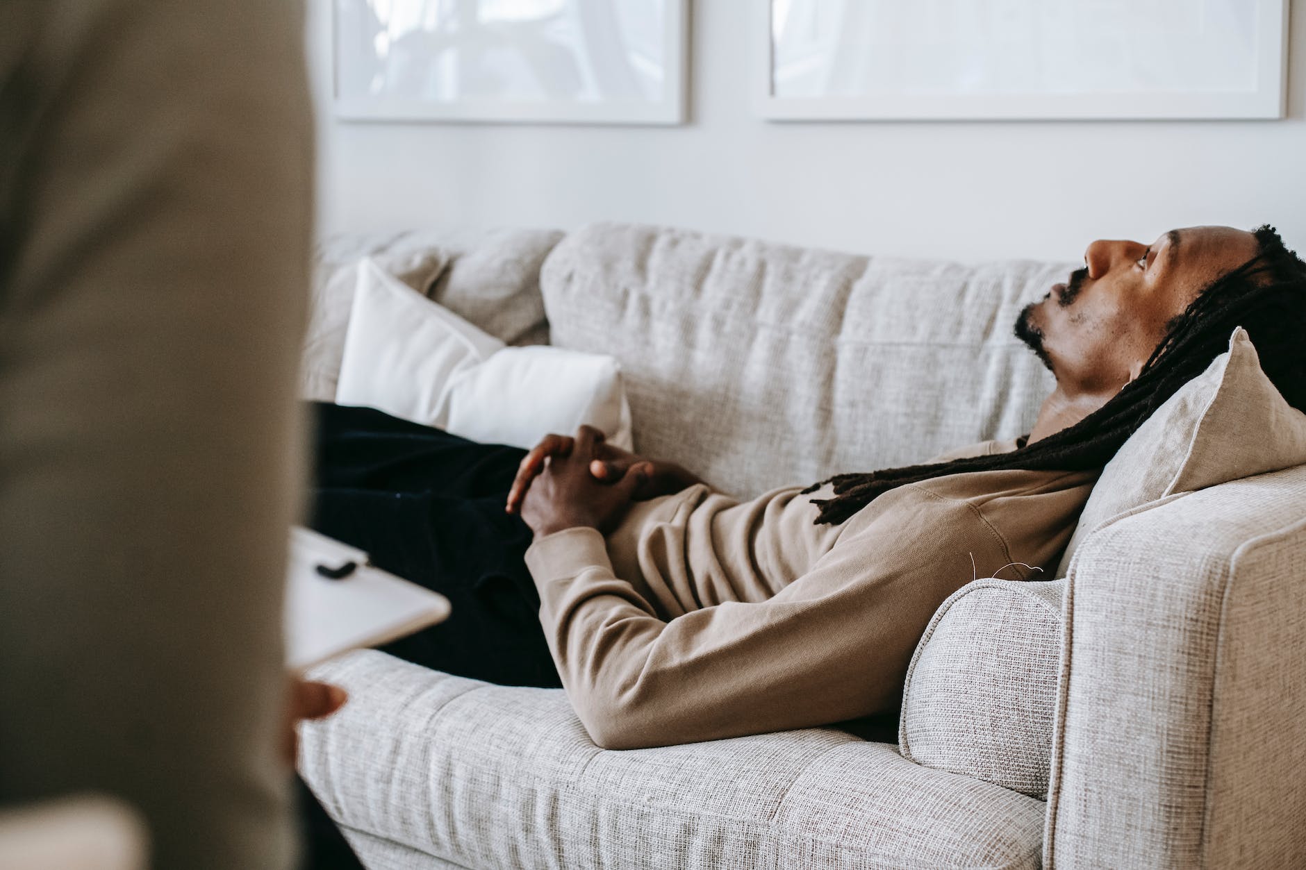 crop black man lying on sofa in psychotherapist office