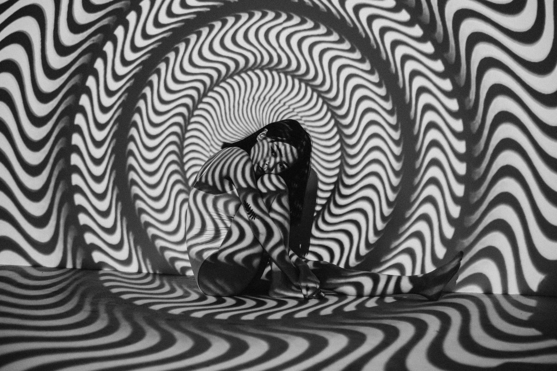 woman sitting near black and white striped wall